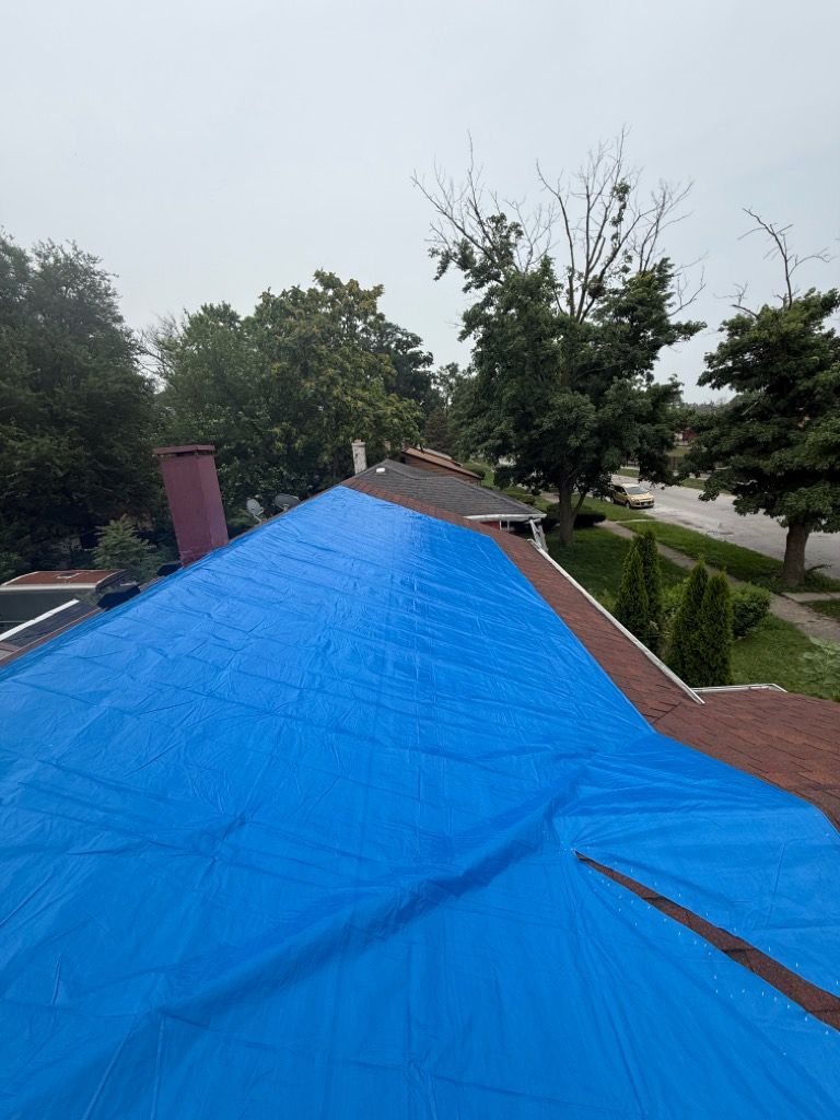 Blue emergency tarp secured over a damaged roof